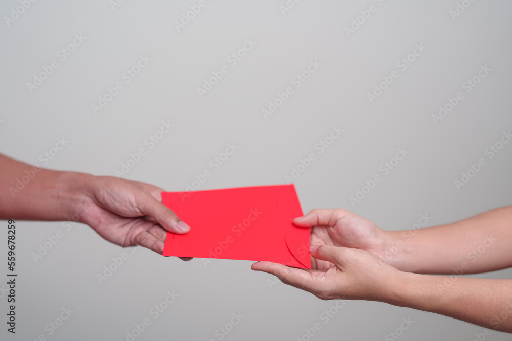 Obraz premium People hand giving Chinese red envelope, money gift for happy Lunar New Year holiday