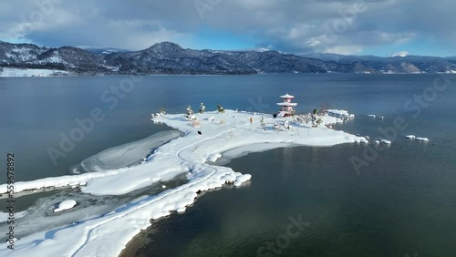 tranquil clear mountain lake in winter, aerial view of lake Toya in Hokkaido with a Japanese pagoda in the snow, peaceful scenic winter scene photo