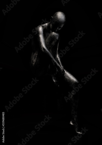 Female figure with cracked metallic skin holding one knee, face down. 3D illustration.