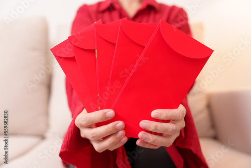 Woman holding Chinese red envelope, money gift for happy Lunar New Year holiday