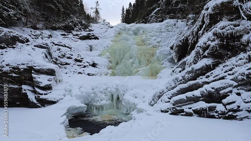 Big and frozen waterfall Dolanfossen on river Homla in Norway. Winter time magic. Beautiful snow and ice. photo