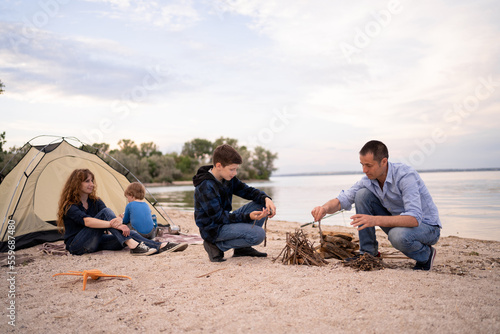 Party, Camping of family with children, relaxing and firewood in campfire near tent on the sea shore