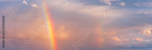 Panoramic background of stormy sky with rainbow and dramatic clouds at sunset © AVTG