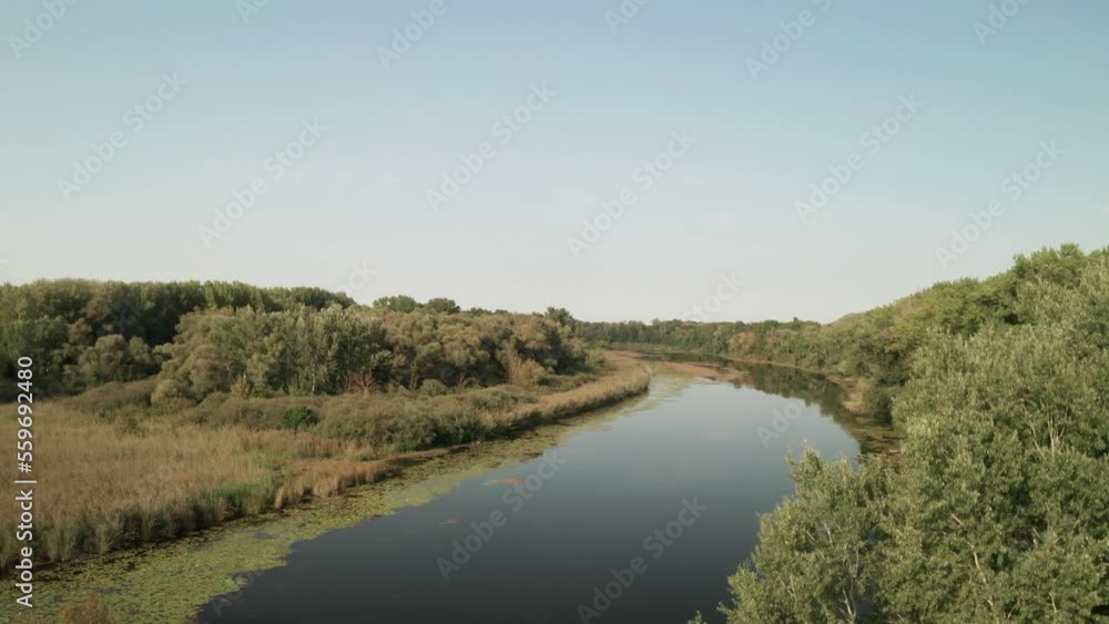 Aerial reveal shot of a river channel near the Cicovske lake near the Danube river in Central Europe. Drone is ascending and tilting the camera down revelaing the channel. Aerial reveal shot of a river channel near the Cicovske lake near the Danube river in Central Europe. Drone is ascending and tilting the camera down revelaing the channel.