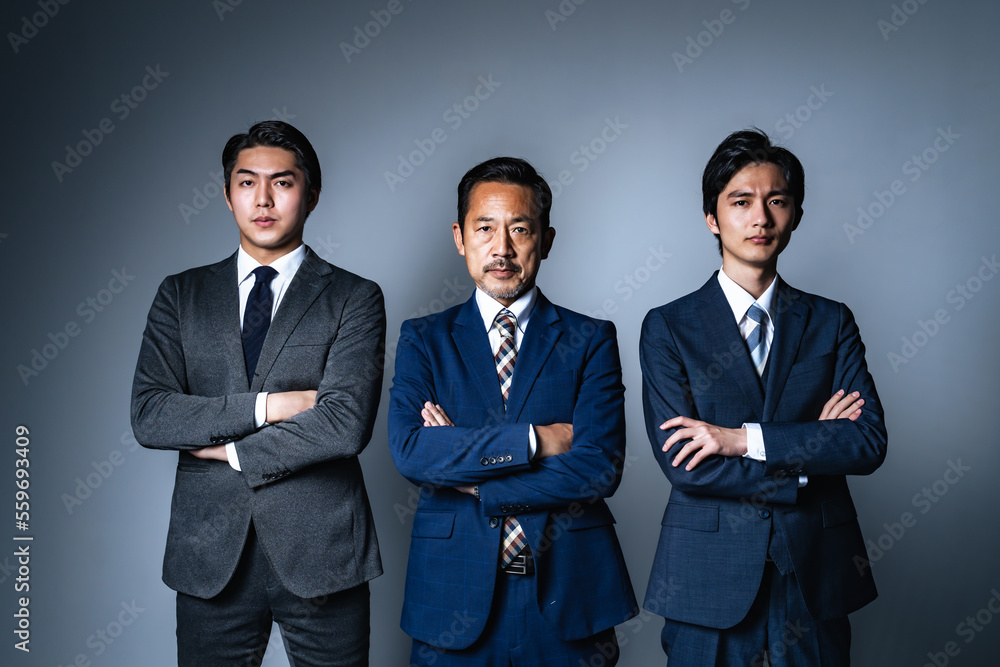 腕組みして並ぶ幅広い世代のビジネスマン StockFoto Adobe Stock