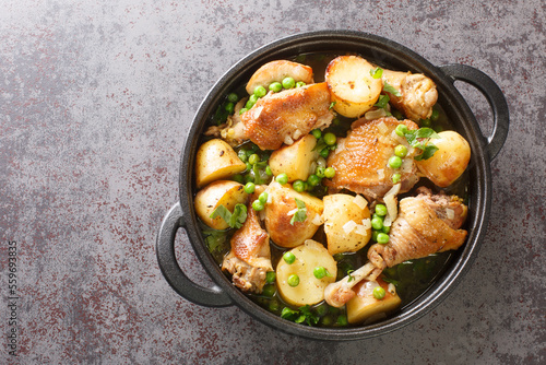 Chicken Vesuvio is pan-seared and baked chicken, potatoes, and peas with a ridiculously delicious herbed wine sauce close-up in a frying pan on the table. Horizontal top view from above