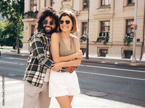 Smiling beautiful woman and her handsome boyfriend. Sexy cheerful family having tender moments in the street at sunset. Models hugging. Embracing each other. Love concept. In sunglasses