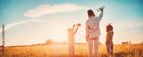 Foto Father with his children playing with toy of plane on the evening field