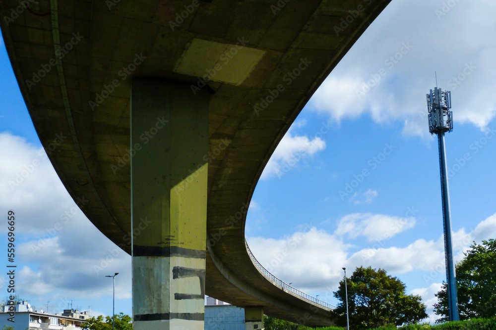 concrete overpass highway underside view with heavy column. low angel view. street lights and blue sky with white clouds. curving high speed road. transportation concept. diminishing perspective concrete overpass highway underside view with heavy column. low angel view. street lights and blue sky with white clouds. curving high speed road. transportation concept. diminishing perspective