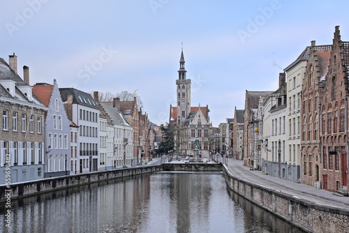 Old medieval houses and Poortersloge tower along a canal in Bruges
