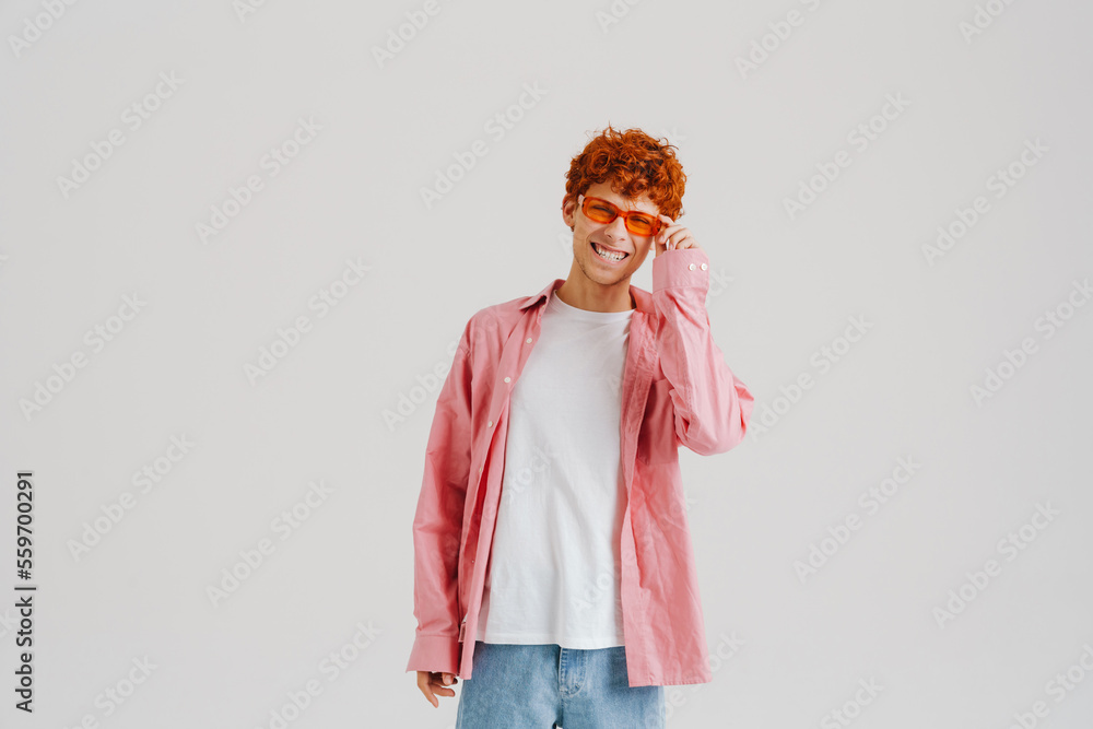 Young ginger man wearing sunglasses smiling and looking at camera Young ginger man wearing sunglasses smiling and looking at camera