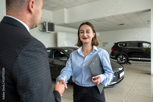 bbusiness client shaking hands with sales agent in suit after buying a car in showroom photo