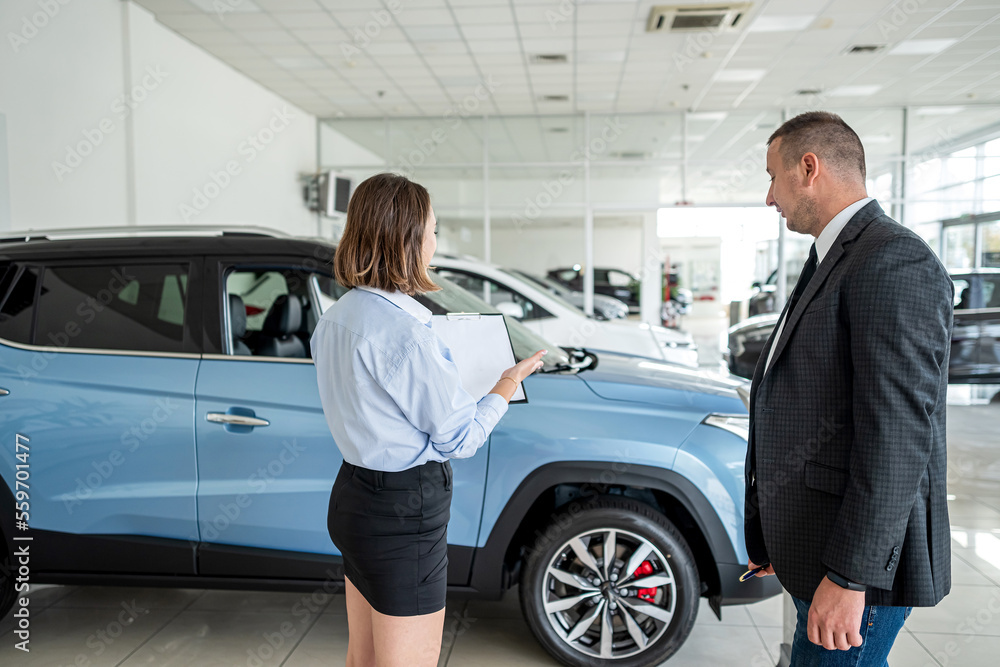 young manager in suit holding clipboard with female client talking to sales modern car young manager in suit holding clipboard with female client talking to sales modern car