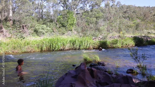 A father and son swim in a flowing river while camping in the Australian bush. photo