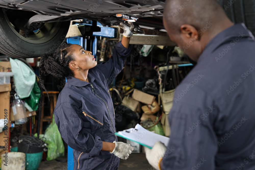 Group of car mechanic in uniform checking maintenance a lifted car service with clipboard at repair garage station. Worker holding wrench and fixing breakdown vehicle. Car repair service concept Group of car mechanic in uniform checking maintenance a lifted car service with clipboard at repair garage station. Worker holding wrench and fixing breakdown vehicle. Car repair service concept
