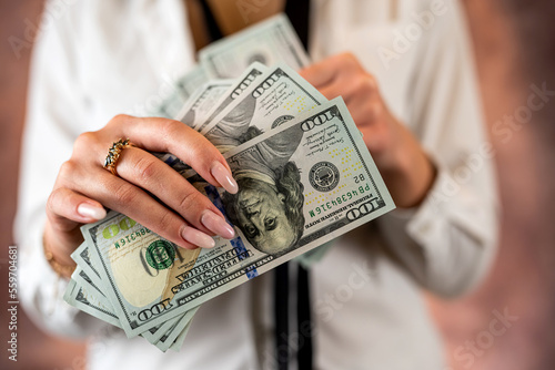 Canvas-taulu Cropped photo of a woman holding US dollar money in her hands on the background of her body