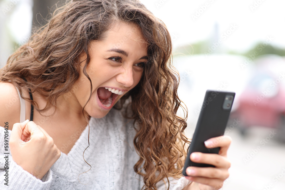 Excited woman celebrating checking phone