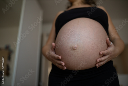 Pregnant female caressing her belly. Prenatal concept. Very close-up front view