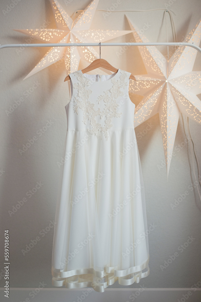 White festive dress hanging on a wooden hanger White festive dress hanging on a wooden hanger