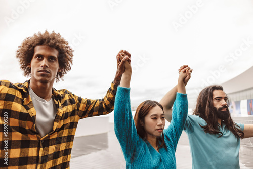 Multiracial activists holding hands standing with each other