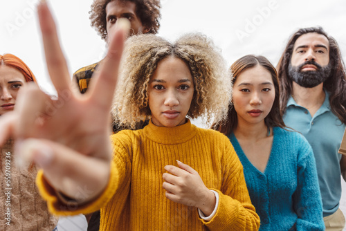 Woman showing peace sign with diverse protestors photo