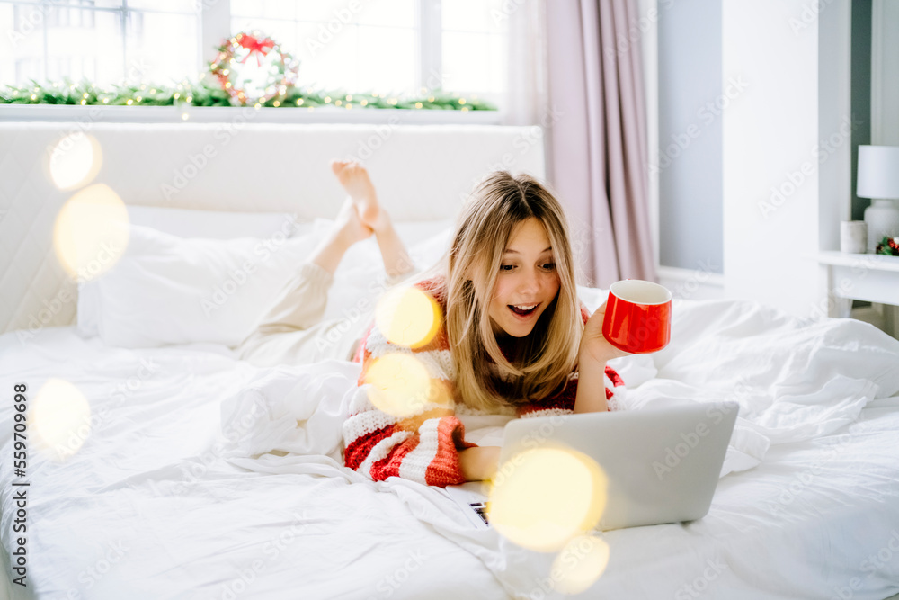 Surprised girl using laptop lying on bed at home Surprised girl using laptop lying on bed at home