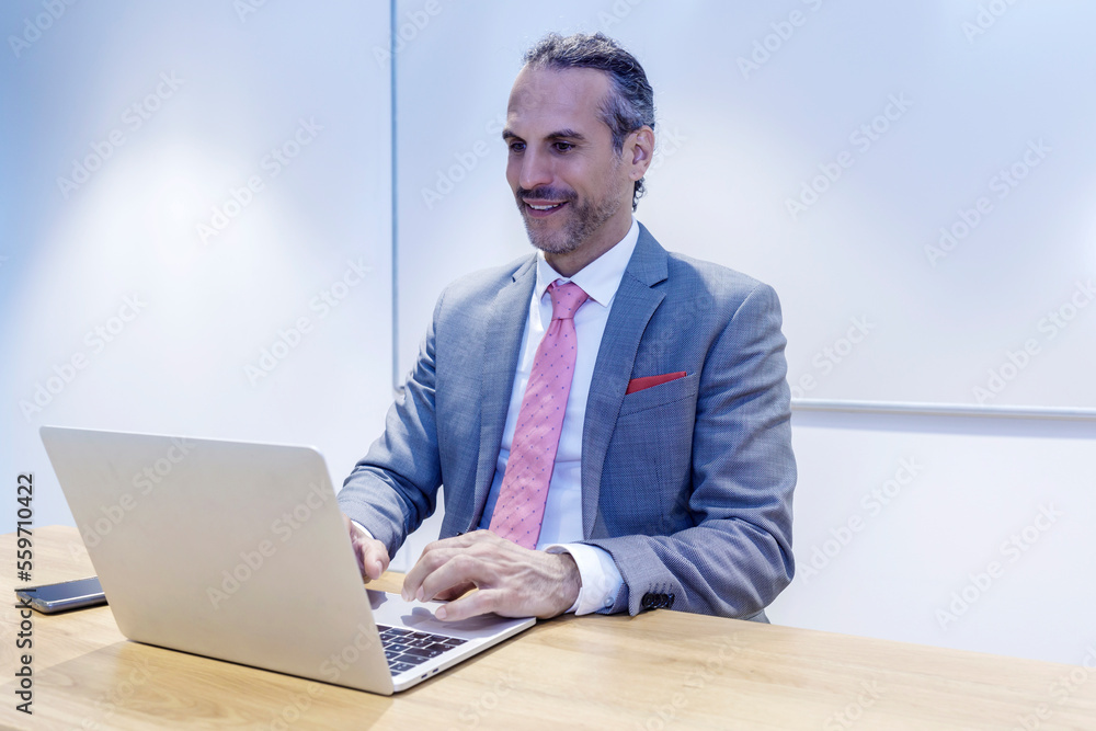 Smiling businessman working on laptop in office Smiling businessman working on laptop in office