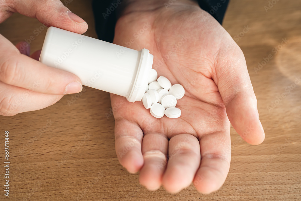 A lot of white pills in the hands of an adult man. A lot of white pills in the hands of an adult man.