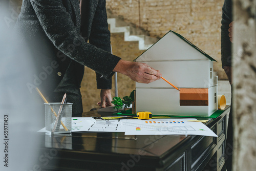 Architect showing insulation on model house on desk at construction site photo