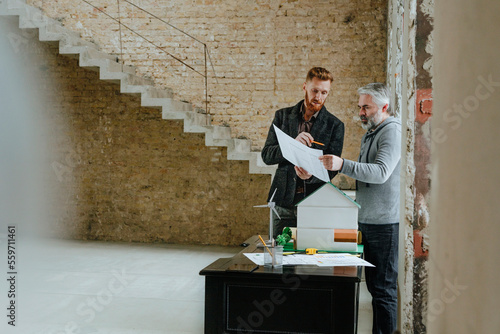 Businessman explaining blueprint to customer at construction site photo