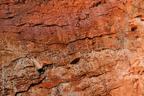 Stony background. Ragged texture. Macro shooting. Rough red brown wall with cracks and rusty cement effect.