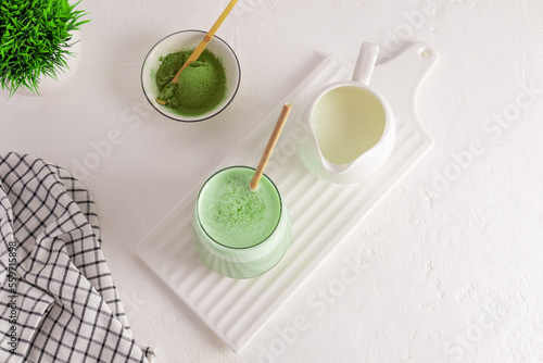 tea ceremony. matcha latte green tea with milk in a glass on a white ceramic board, a jug of milk, a bowl of green powder. an alternative to coffee.