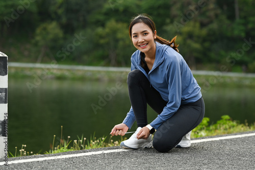 Attractive asian woman tying shoelace before running outdoors. Fitness, sport and healthy lifestyle concept