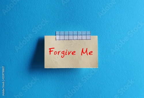 Photos Old note paper stick on blue background with note written FORGIVE ME, to ask som