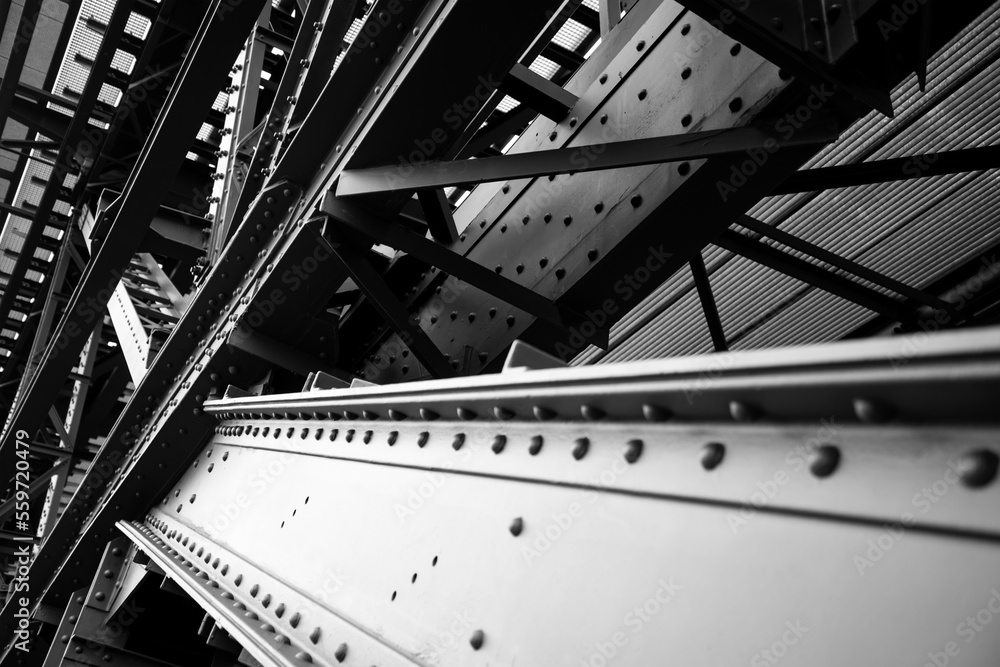 Steel beams with rivets and screws forming the compilicated construction of the historic “Müngstener Brücke“ railway bridge in Solingen Germany from 1897. Frog perspective in black and white.