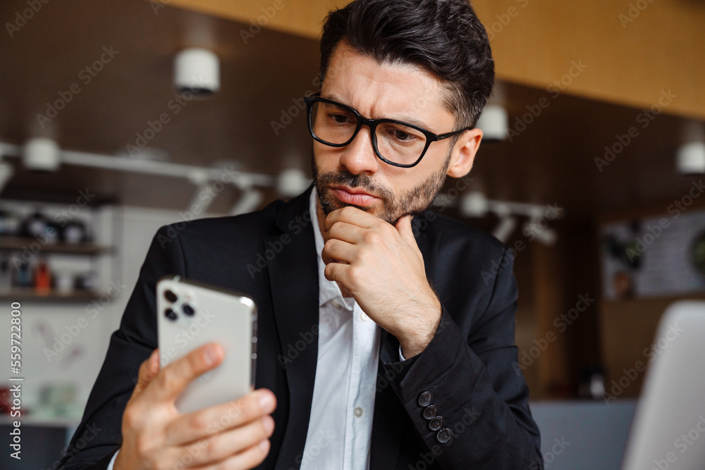 Young businessman using mobile phone while working at office Young businessman using mobile phone while working at office