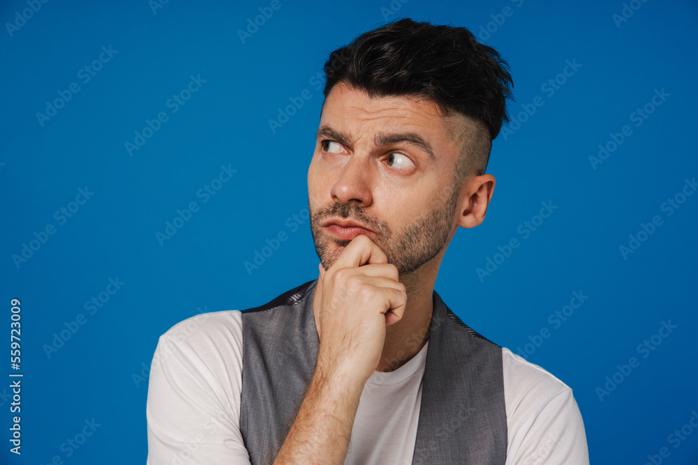 Young white man touching his chin and looking aside Young white man touching his chin and looking aside
