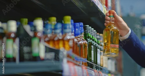 man buying whiskey in liquor store, closeup view of male hand taking bottle from shelf, 4K, Prores