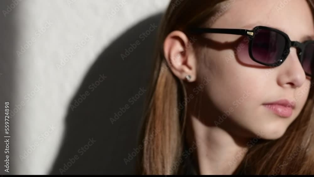 Slow motion video of a stylish child in leather jacket with glasses on dark background with a shadows Slow motion video of a stylish child in leather jacket with glasses on dark background with a shadows