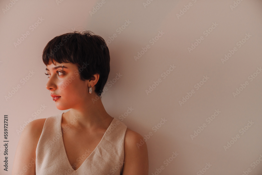 Young beautiful short-haired woman looking aside while standing indoors Young beautiful short-haired woman looking aside while standing indoors