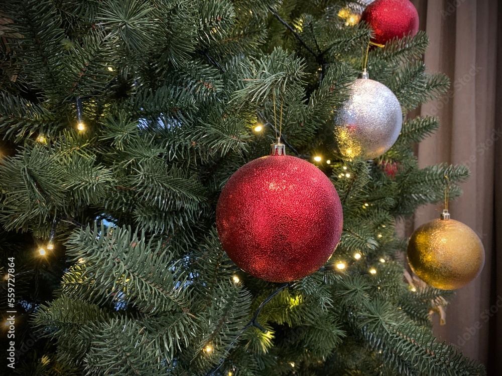 Shiny ball on a Christmas tree with garlands, close-up. Concept: winter weekend and new year holidays. Christmas tree decoration on Christmas Eve. Shiny ball on a Christmas tree with garlands, close-up. Concept: winter weekend and new year holidays. Christmas tree decoration on Christmas Eve.