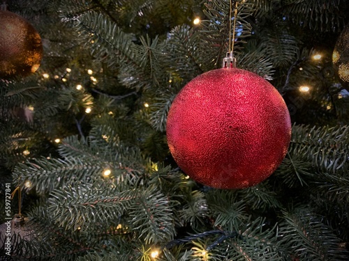 Shiny ball on a Christmas tree with garlands, close-up. Concept: winter weekend and new year holidays. Christmas tree decoration on Christmas Eve.