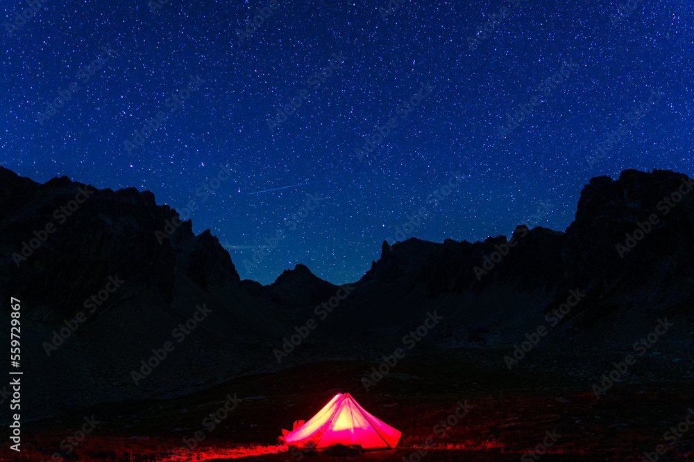 A tent pitched in the mountains of Névache, a commune in the Hautes-Alpes department in southeastern France. The night sky is filled with stars and the Milky Way