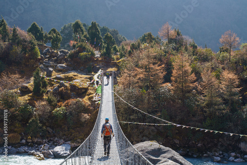 A hiker crosses a hanging bridge on the Kanchenjunga base camp trek in Nepal to Ghunsa during autumn. photo