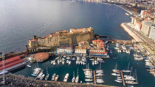 Aerial view of Castel dell'Ovo, a seafront castle located on a peninsula on the Gulf of Naples, Italy. There's a small fishing village called Borgo Marinaro, developed around the castle's eastern wall