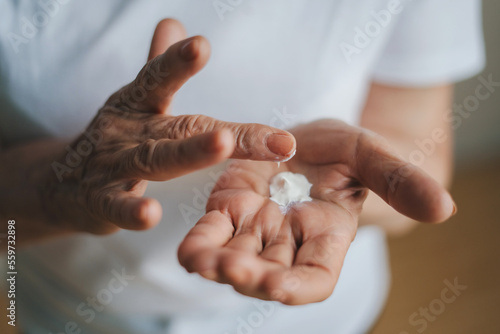 Older woman applying cream on hands. Closeup portrait. Therapy treatment, beauty skin care. Anti-aging skincare. Anti-aging skin lifting beauty.