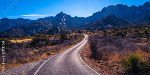 Organ Mountains, Desert Peaks National Monument in Las Cruces, Doña Ana County, New Mexico, Southwestern USA, curved single lane paved road to Sugarloaf Peak through arid desert valley meadow at dusk.