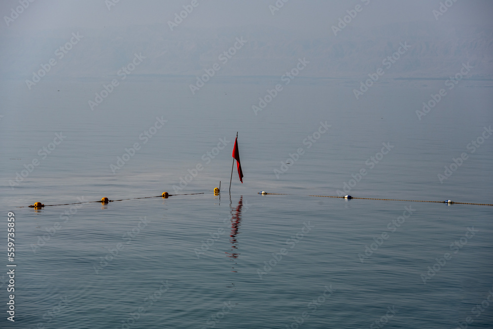 red flag and restrictive buoys on calm waters of the Mortvoe Sea