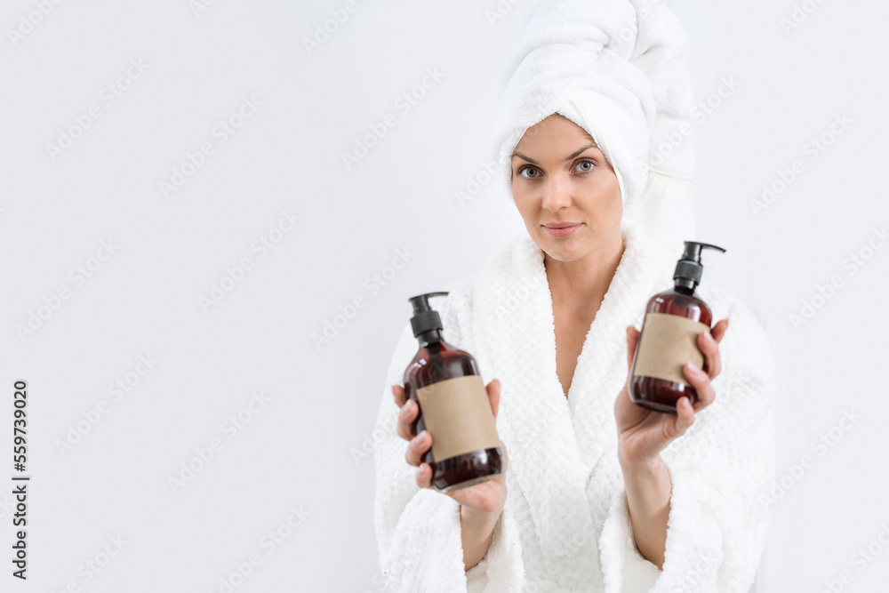 Female in white bathrobe showing dispenser bottles with template label Female in white bathrobe showing dispenser bottles with template label