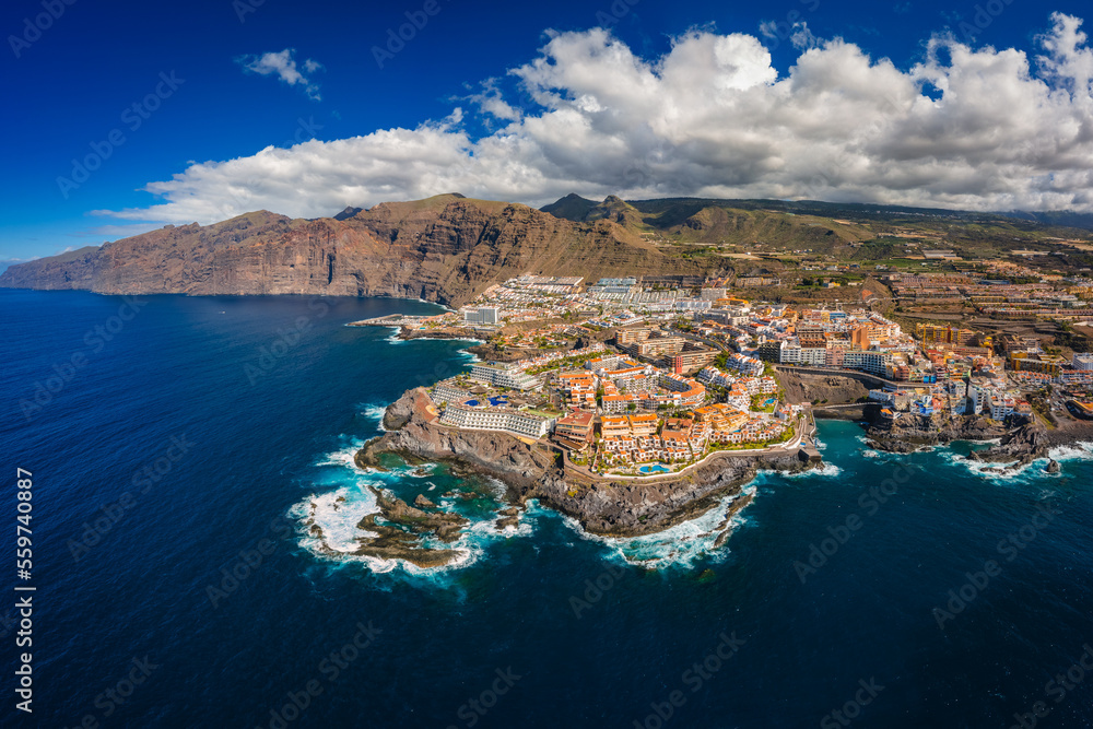 Aerial view of the city of Los Gigantes and the surrounding majestic cliffs. Sunny weather highlights the colors of the water.